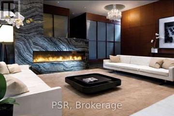 Toronto (Bay Street Corridor) condo for rent - A modern living room with a fireplace and a white couch.