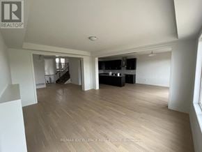 Kitchener apartment for rent - A spacious room with wooden flooring and a kitchen area in the background.