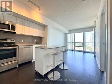 Toronto (Mimico) condo for rent - A modern kitchen with white cabinets and stainless steel appliances.
