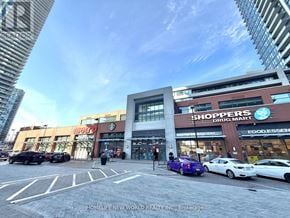 Toronto (Mimico) condo for rent - A city street with a Shoppers Drug Mart and a Mclub storefront.