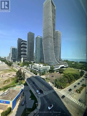 Toronto (Mimico) condo for rent - A cityscape with a mix of modern and older buildings, a busy road, and a clear sky.