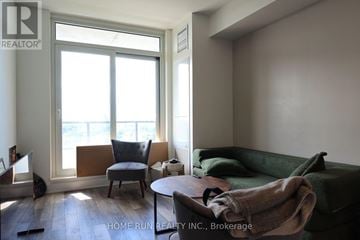 Ottawa condo for rent - A living room with a green couch and a chair by a window.