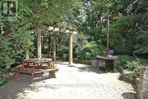 Mississauga (City Centre) condo for rent - A wooden picnic table is set up under a pergola in a backyard.