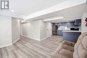 Ajax (Central West) apartment for rent - A spacious living room with a grey kitchen in the background.