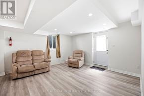 Ajax (Central West) apartment for rent - A living room with a couch, chair, and a fire extinguisher on the wall.
