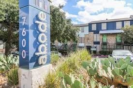 San Antonio apartment for rent - A blue and white sign with the word "abode" on it stands in front of a building.
