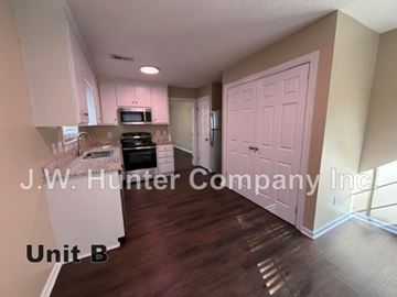 Wilson apartment for rent - A kitchen with white cabinets and a pink door.