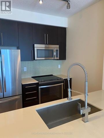 Mississauga (City Centre) condo for rent - A kitchen with a stainless steel refrigerator and a black microwave above the stove.