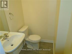 Thorold (Rolling Meadows) townhouse for rent - A white toilet sits next to a sink in a small bathroom.