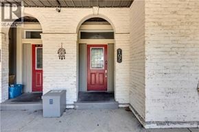 Brantford apartment for rent - A white building with a red door and a small grey box in front.