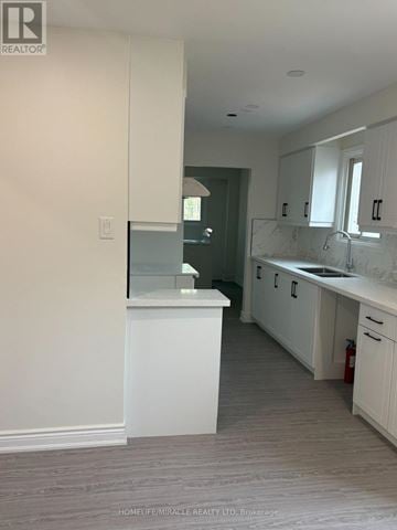 Barrie (Grove East) apartment for rent - A kitchen with white cabinets and a marble countertop.