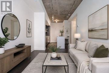Toronto (Niagara) condo for rent - A living room with a white couch, a coffee table, and a large painting on the wall.