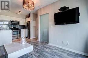 Toronto (Niagara) condo for rent - A modern kitchen with a white island and a flat screen TV mounted on the wall.