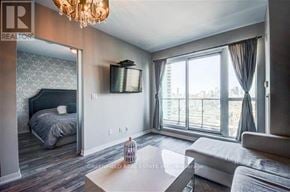 Toronto (Niagara) condo for rent - A well-lit bedroom with a large bed and a flat-screen TV mounted on the wall.