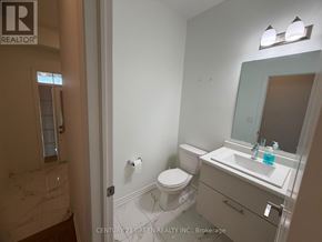 Whitby townhouse for rent - A bathroom with a toilet, sink, and mirror.