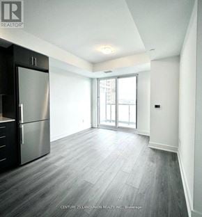 Oshawa (Windfields) condo for rent - A spacious kitchen with a stainless steel refrigerator and wooden flooring.