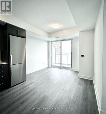 Oshawa (Windfields) condo for rent - A spacious kitchen with a stainless steel refrigerator and wooden flooring.