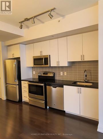 Markham (Thornhill) condo for rent - A kitchen with white cabinets and a black counter top.
