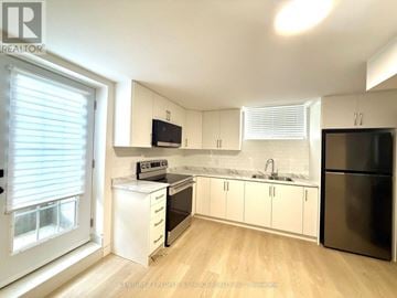 Pelham (Fonthill) townhouse for rent - A kitchen with white cabinets and a black fridge.