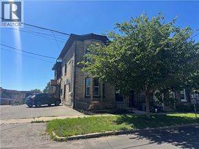 Brantford apartment for rent - A black car is parked in front of a brick building with a tree in front of it.