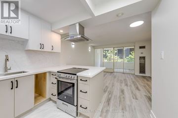 Toronto (Bay Street Corridor) condo for rent - A modern kitchen with white cabinets and a black stove top oven.