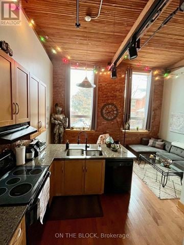 Guelph (St. Patrick's Ward) condo for rent - A kitchen with wooden cabinets and a black stove top oven.