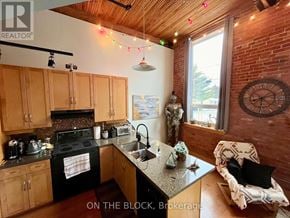 Guelph (St. Patrick's Ward) condo for rent - A kitchen with wooden cabinets and a black stove top oven.