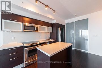 Toronto (Bay Street Corridor) condo for rent - A modern kitchen with dark wood cabinets and stainless steel appliances.