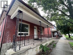 Brantford apartment for rent - A red brick house with a white roof and a black iron fence.