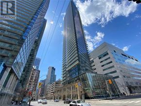 Toronto (Bay Street Corridor) condo for rent - A tall glass building stands in the middle of a city intersection.