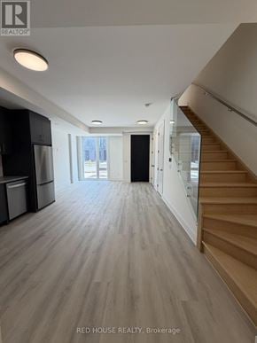 St. Catharines (Oakdale) townhouse for rent - A spacious room with wooden flooring and a staircase on the right side.