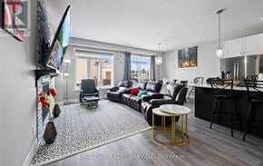Woodstock (Woodstock - North) townhouse for rent - A living room with a black couch and a TV mounted on the wall.