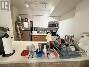 Toronto (Bay Street Corridor) condo for rent - A kitchen counter with various items on it and a refrigerator in the background.
