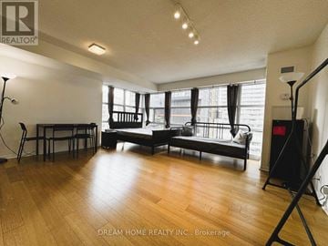 Toronto (Bay Street Corridor) condo for rent - A living room with a black sofa and wooden floors.