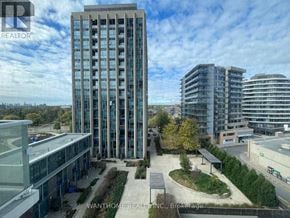 Toronto (Banbury-Don Mills) condo for rent - A tall building with many windows is surrounded by other buildings.