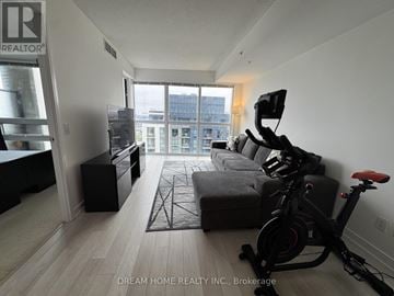 Toronto (Islington-City Centre West) condo for rent - A living room with a grey sofa and a black exercise bike.