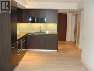 Toronto (Waterfront Communities) condo for rent - A kitchen with dark wood cabinets and a black refrigerator.