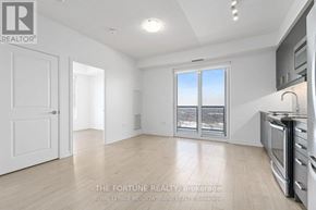 Mississauga (Hurontario) condo for rent - A well-lit, empty room with a kitchen area to the right and a door to the left.