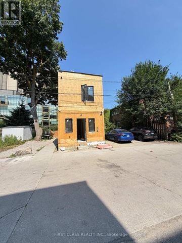 Toronto (University) apartment for rent - A small wooden building with a black window and a door is in the middle of a parking lot.