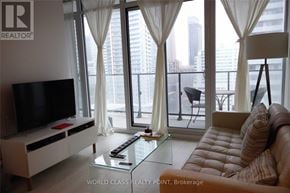 Toronto (Waterfront Communities) condo for rent - A living room with a television, a couch, and a glass table.