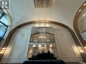 Markham (Unionville) condo for rent - A chandelier hangs from the ceiling above a reception desk in a building.