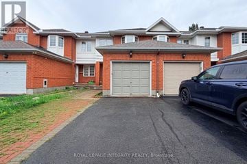 Ottawa townhouse for rent - A blue car is parked in front of a house with a garage door.