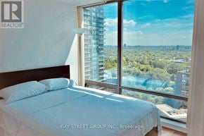 Toronto (Annex) condo for rent - A bedroom with a large window overlooking a cityscape.