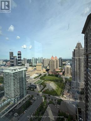 Mississauga (City Centre) condo for rent - A cityscape with a mix of modern and older buildings, with a clear sky and a few clouds.