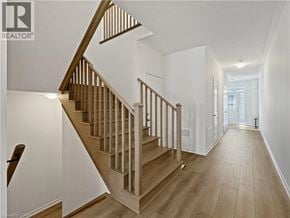 Cambridge townhouse for rent - A wooden staircase with a white wall on the side and a door in the distance.
