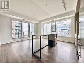 Toronto (Regent Park) condo for rent - A spacious room with wooden flooring and large windows overlooking a cityscape.