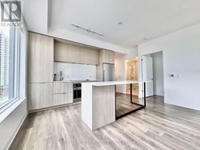 Toronto (Regent Park) condo for rent - A modern kitchen with a central island and wooden flooring.