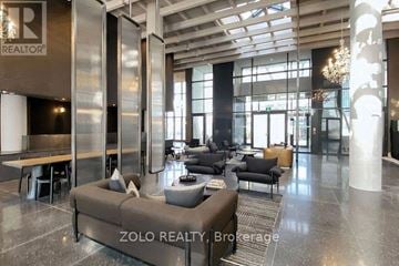 Vaughan (Vaughan Corporate Centre) condo for rent - A modern living room with a large sofa and a chandelier.