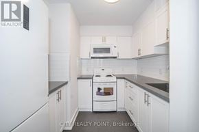 Toronto (Church-Yonge Corridor) condo for rent - A white kitchen with a stove top oven and microwave.