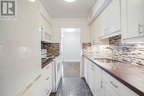 Toronto (Church-Yonge Corridor) condo for rent - A kitchen with white cabinets and a stone backsplash.